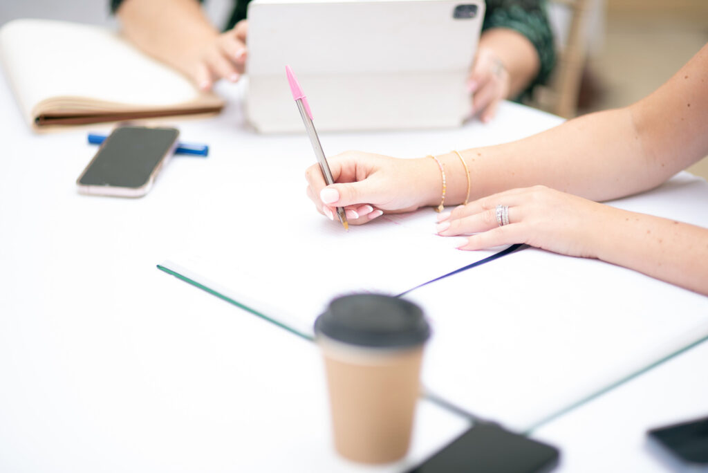 Person writing on a notepad in a collaborative meeting setting