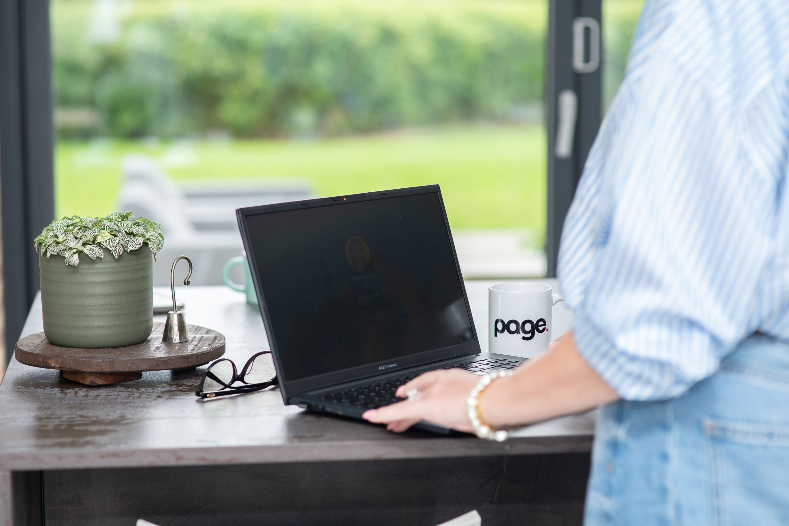 Person on laptop on a kitchen table with page mug