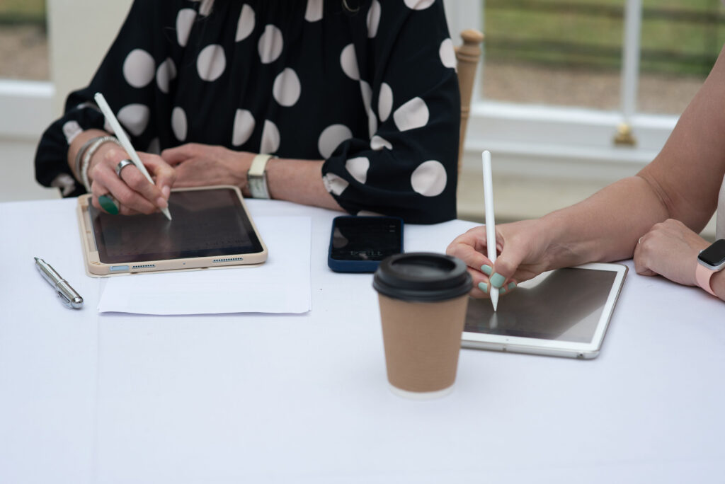 people on table using their ipads with pencils to take notes