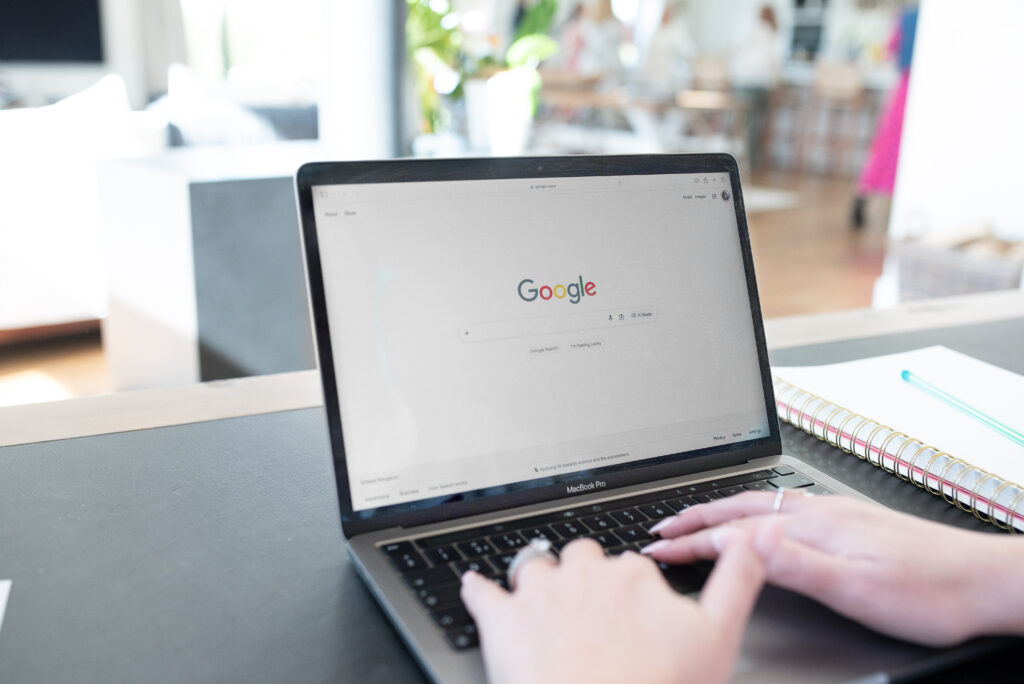 Google search on a MacBook with hands typing on the keyboard